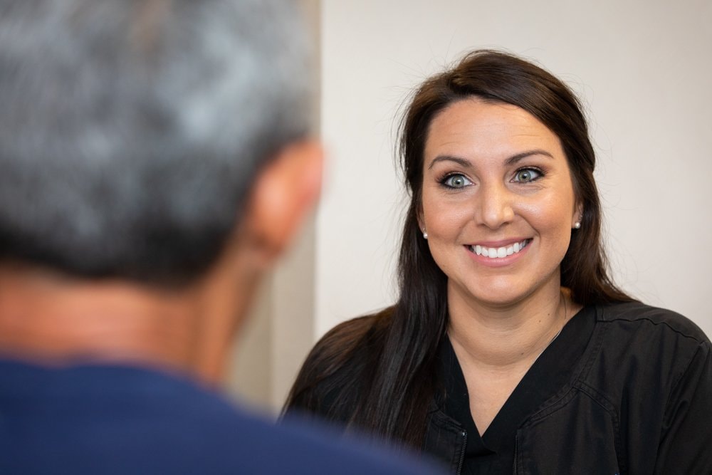 A smiling patient talking with a team member at The Dental Studio of Midland