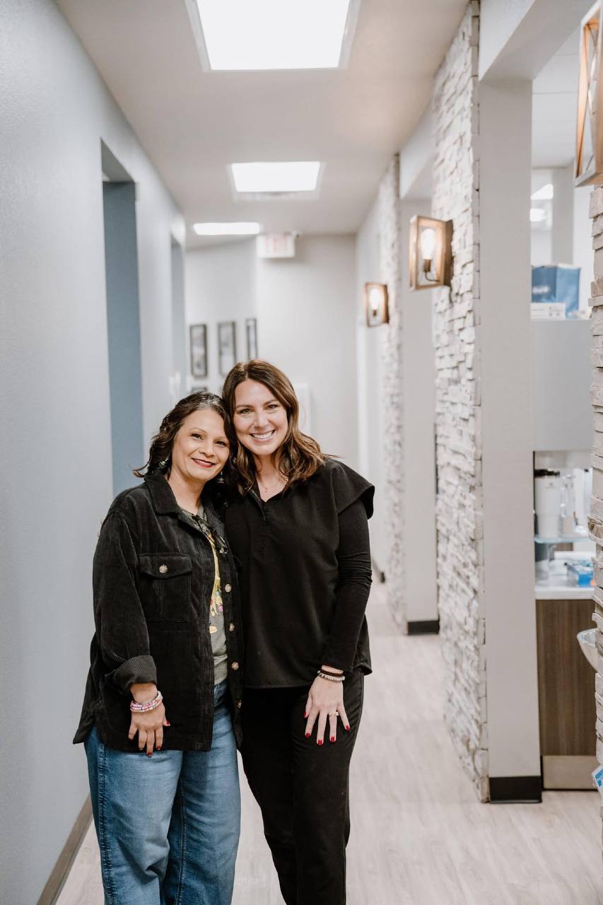 Two members of The Dental Studio of Midland team smiling in the office hallway