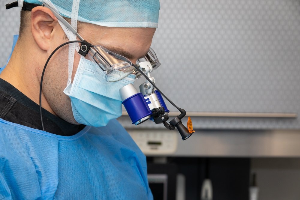 A doctor wearing surgical loupes performing precision dental treatment